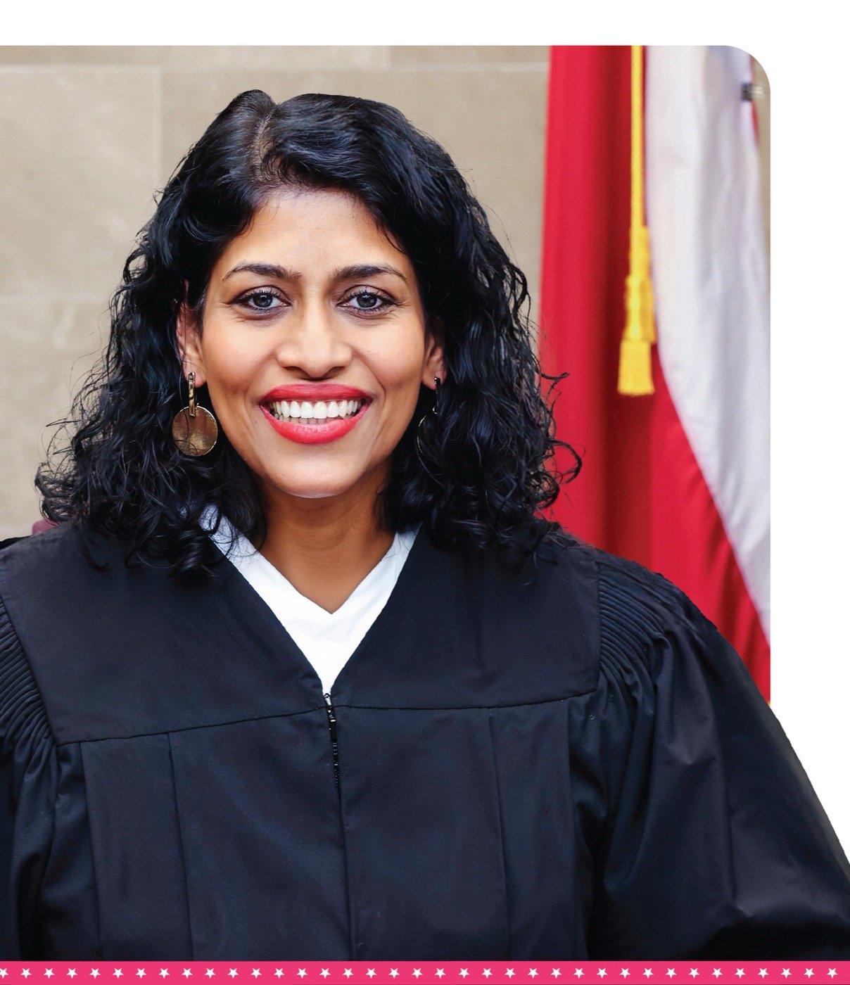 Portrait of Judge Juli Mathew in her judicial robe at the bench with the Texas and U.S. flags in the background
